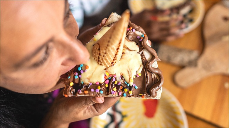 A person eating a piece of ice cream pizza