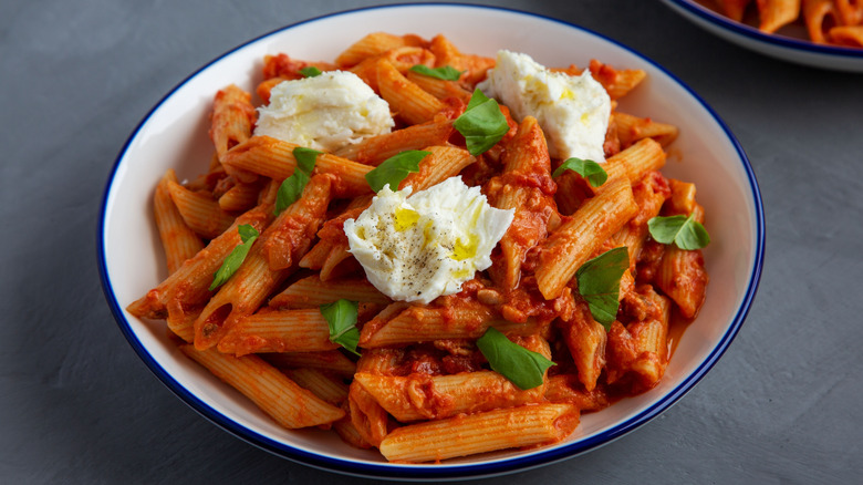 A plate of penne alla vodka garnished with basil and hand-torn mozzarella