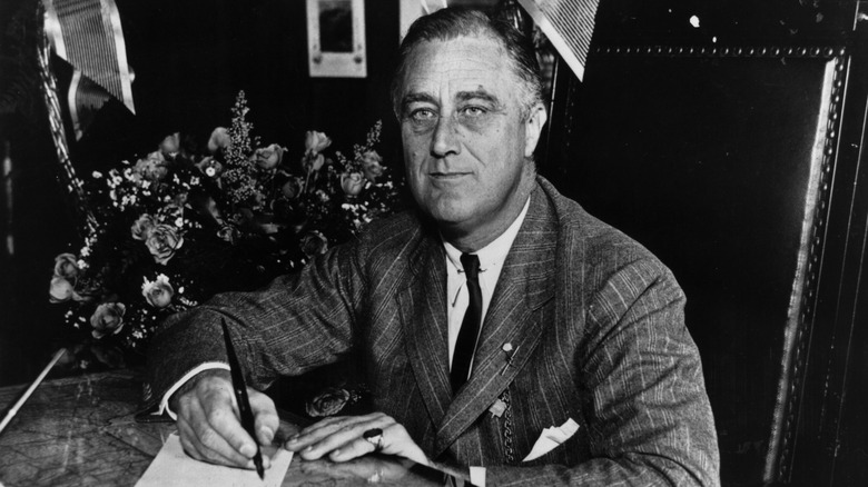 Franklin D. Roosevelt writing at a desk