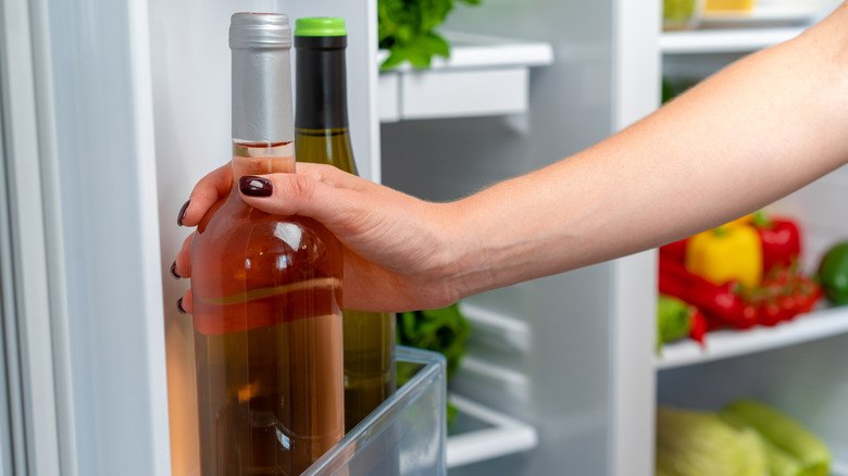 hand taking wine bottle out of freezer