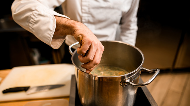 Chef stirring pot of broth