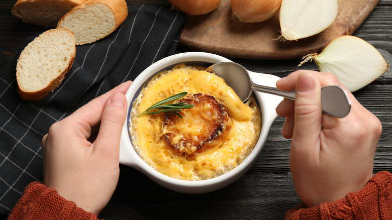 Person spooning French onion soup from bowl