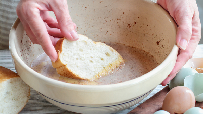 Hands dipping bread in batter