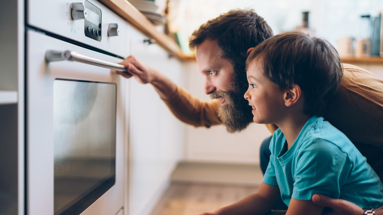 man and child looking into oven