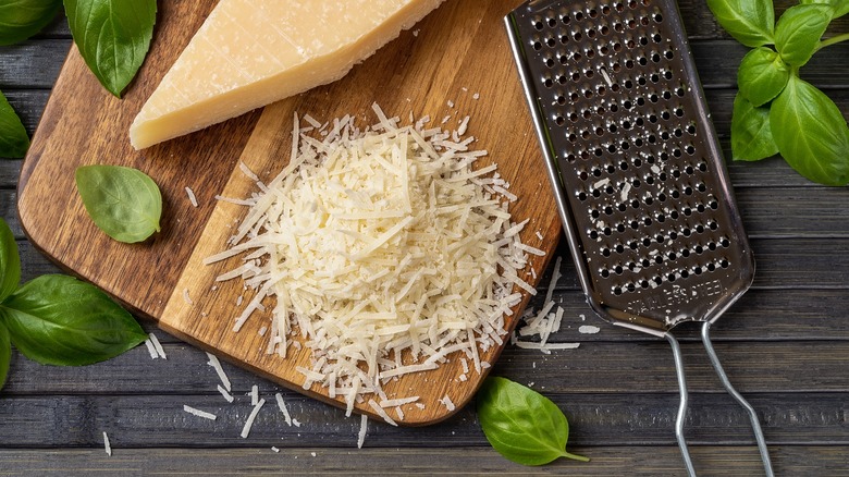 shredded parmesan on a cutting board with hand grater