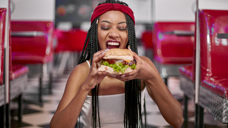 A woman eats a Habit Burger Ahi Tuna Filet sandwich inside a restaurant