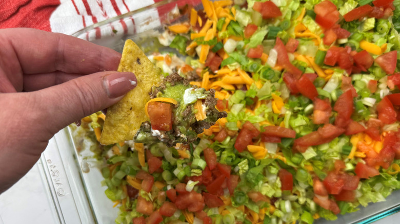 Hand holding tortilla chip with taco dip