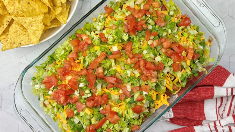 Taco dip with lettuce and tomatoes in large dish