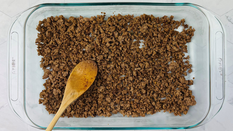 Wooden spoon and ground beef in rectangular dish