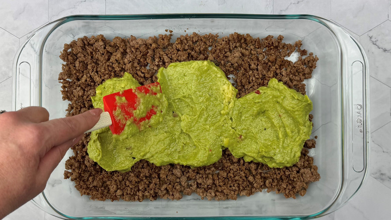 Guacamole on top of beef in large dish