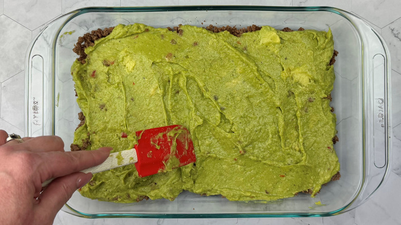 Spatula smoothing out guacamole in large dish