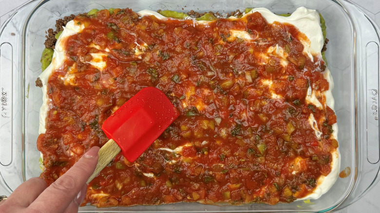 Spatula smoothing out salsa in large dish