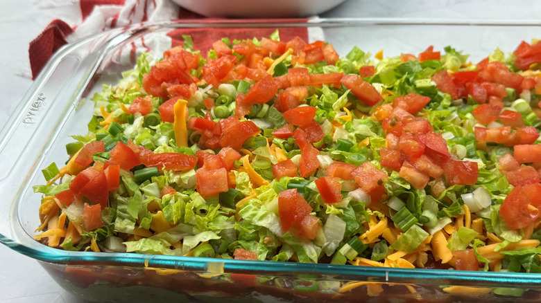 Taco dip with lettuce and tomatoes in large dish