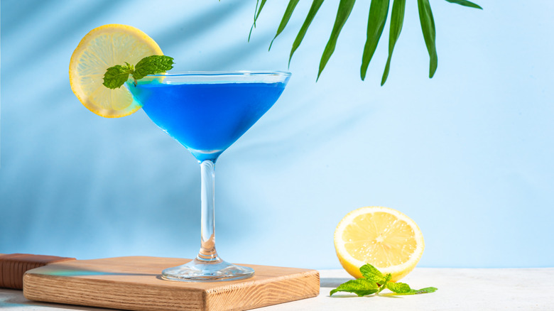 A blue margarita sitting on a cutting board.