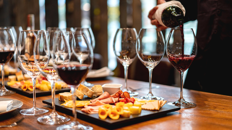 pouring red wine glasses paired with snack board