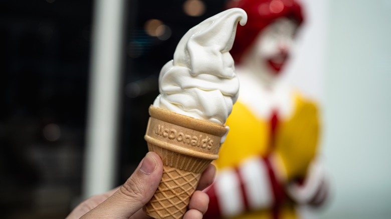 Person holding McDonald's ice cream cone in front of Ronald McDonald