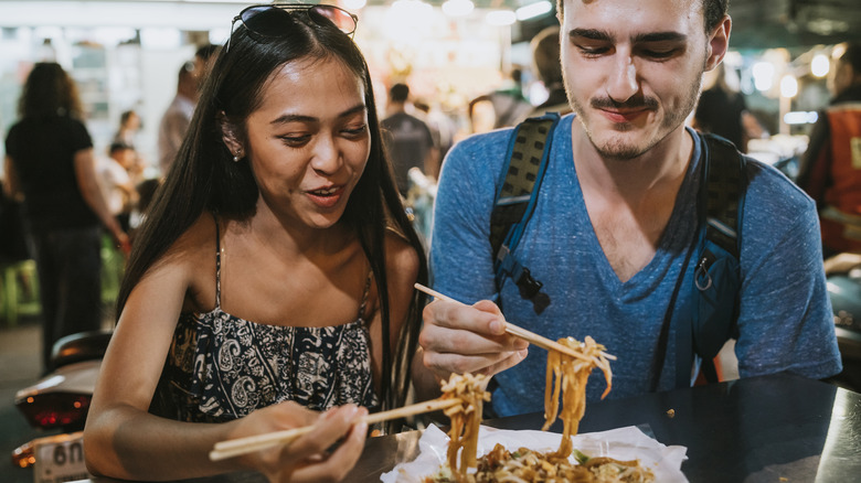 a couple eating at a Bangkok food market