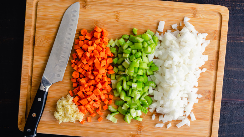 santoku knife next to cut vegetables on cutting board