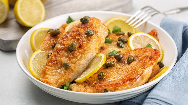 Chicken piccata with capers in white bowl