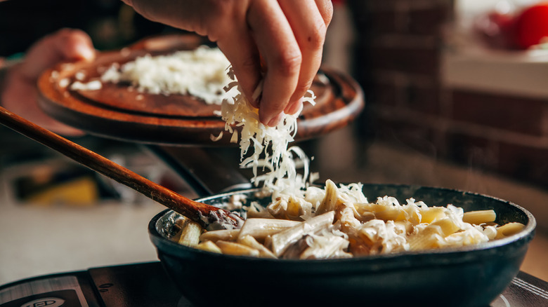 adding cheese to pasta in pan