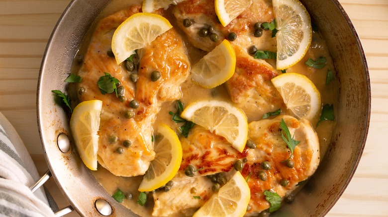 pan of chicken piccata with capers, lemon, and parsley on top