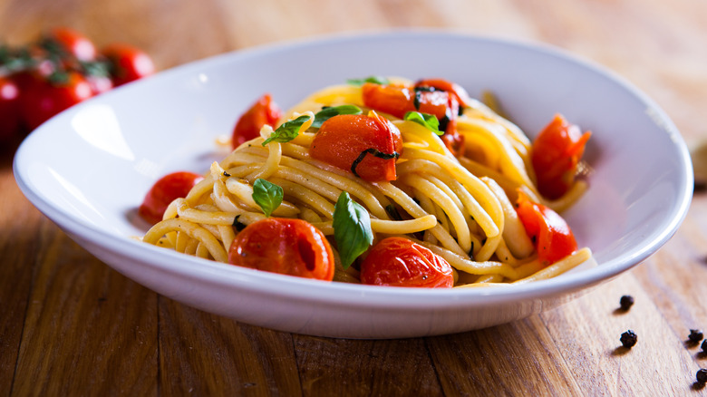 Spaghetti pasta noodles cherry tomatoes and basil