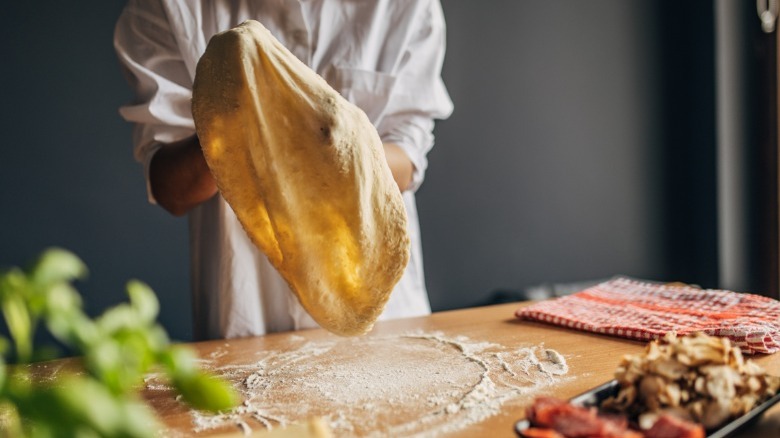 Person throwing pizza dough 