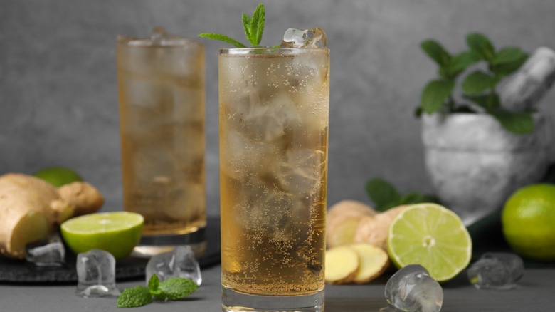 Two glasses of ginger beer with fresh ginger and limes