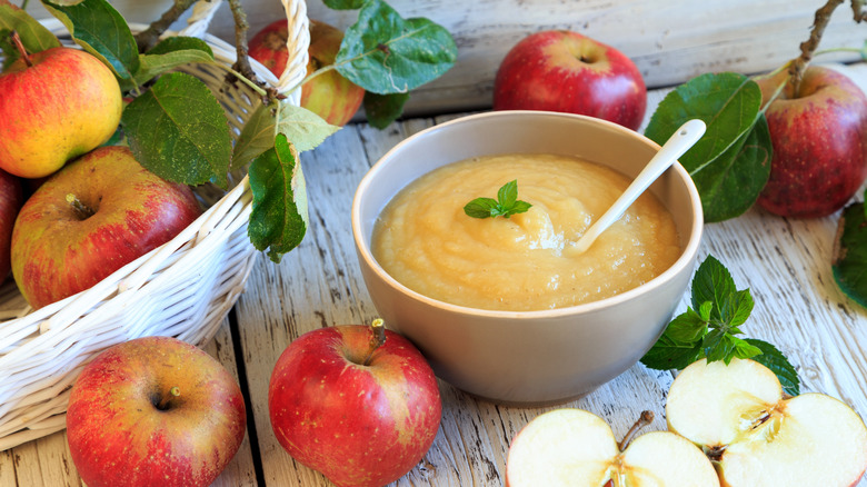 applesauce in a bowl surrounded by apples