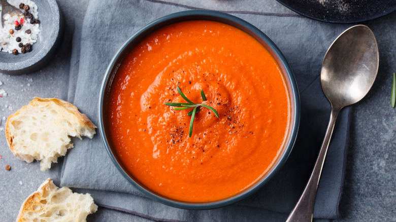 Tomato soup in a bowl with bread and spoon