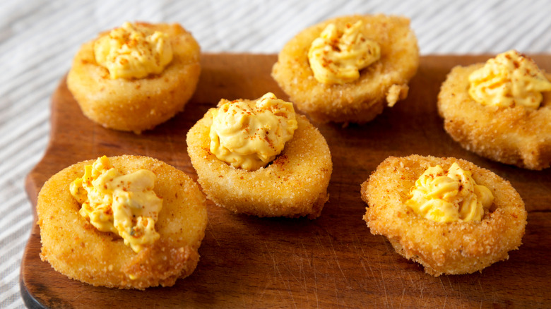 Crunchy fried deviled eggs on wooden board