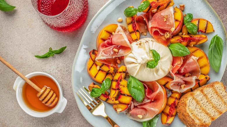 Grilled peach caprese salad with prosciutto and a bowl of honey