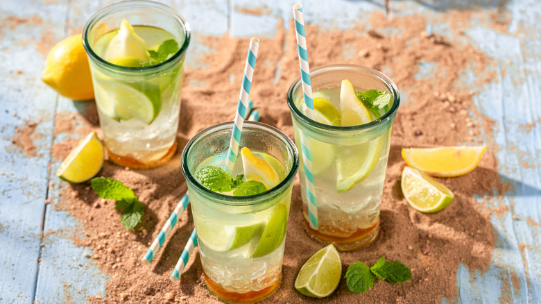 Homemade lemonade with lemons, lime, mint leaves, and white and blue striped straws