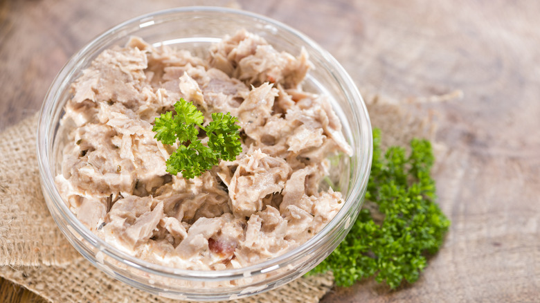 Tuna salad in a glass bowl with herbs