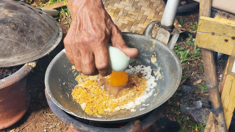 An outdoor cook making kerak telor, or "egg crust"