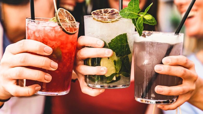 Friends toasting with three different cocktails