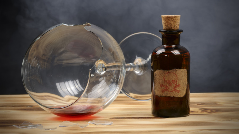 bottle of poison next to broken wine glass