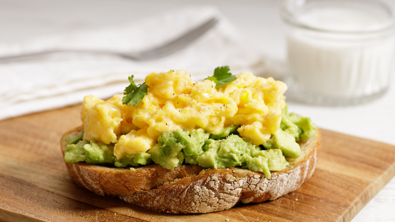 Scrambled egg and avocado on toast with cup of milk