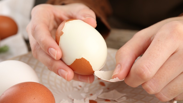 hands peeling boiled egg