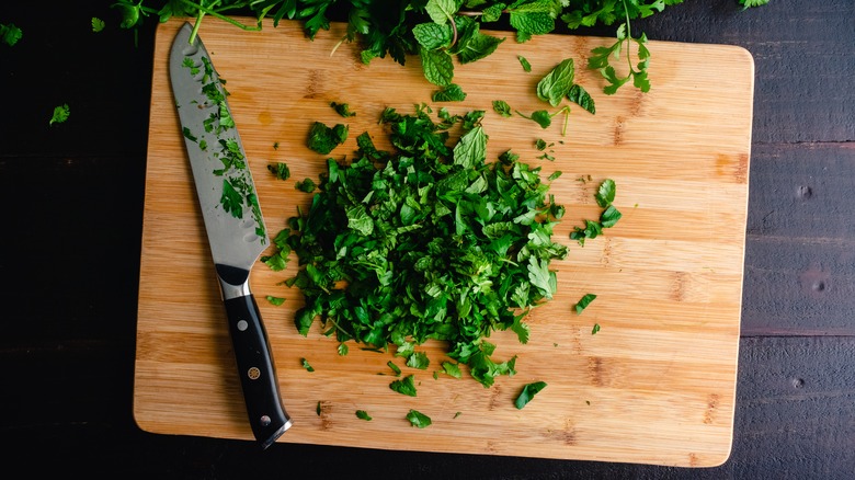 Knife on a cutting board with herbs