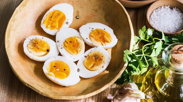 Peeled hard-boiled eggs cut in half in a wooden bowl