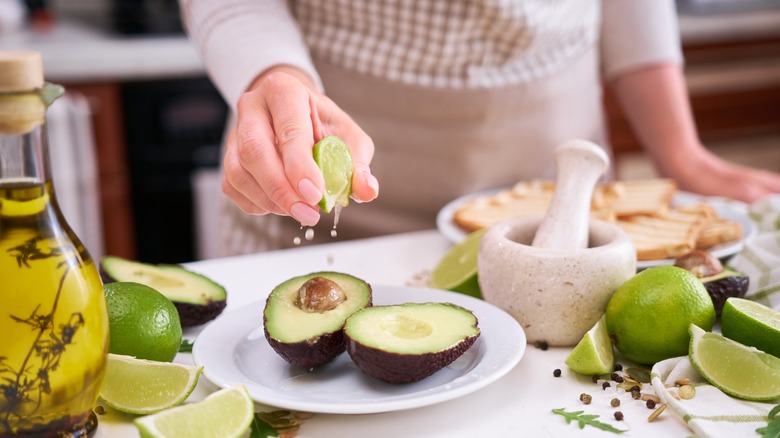 Woman spritzing avocado with lime juice