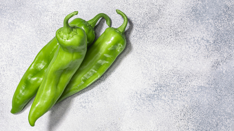 three Hatch green chiles on a grey background