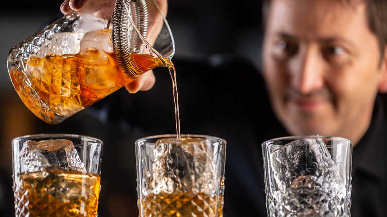 Pouring whiskey cocktails over ice