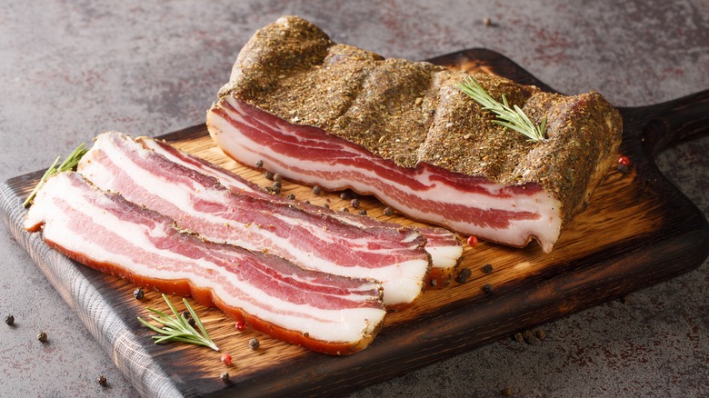 Thick slices of pancetta on cutting board