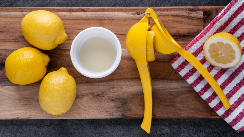 Yellow lemon squeezer with cut lemons on butcher's block