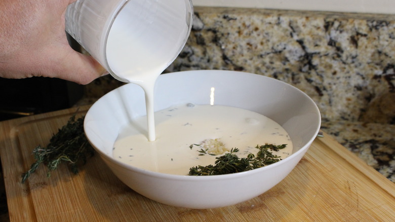 adding cream to bowl of herbs
