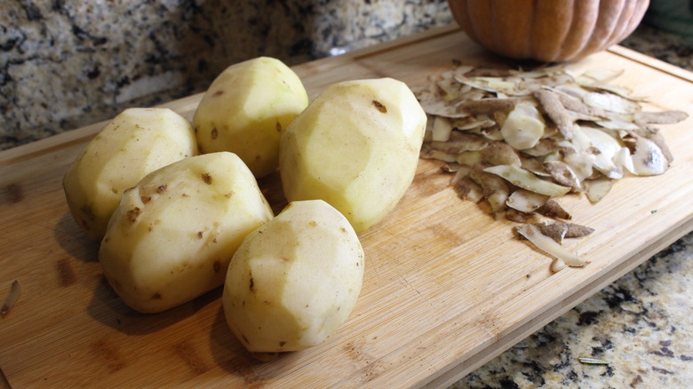 peeled potatoes and peels on cutting board