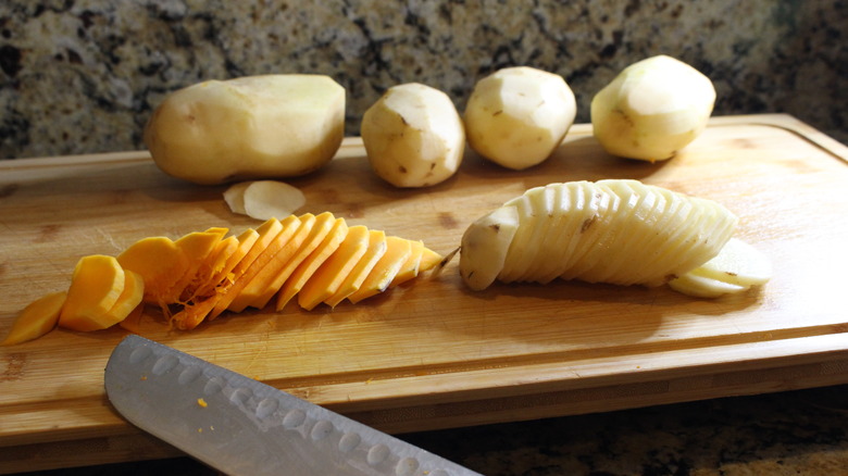 sliced pumpkin and potatoes on cutting board with knife