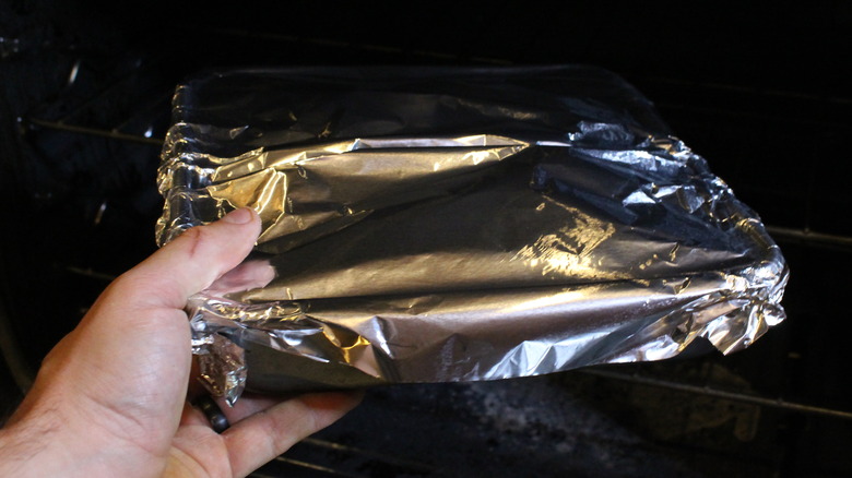 foil-covered dish going into oven